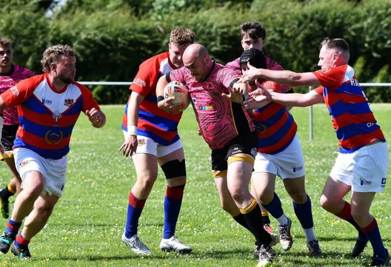 An Aspatria Hornets player in the pink kit held up in a tackle