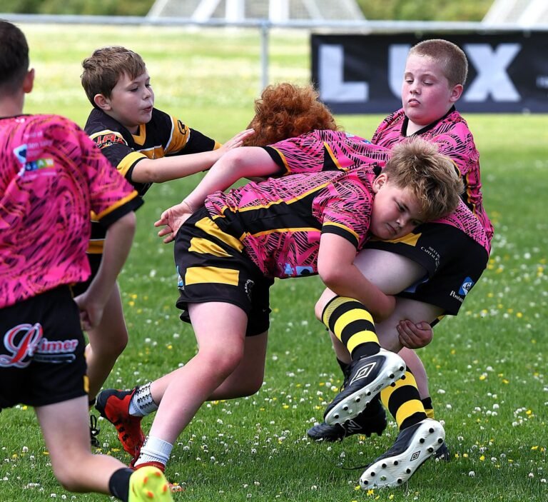 A junior tackle between the pink kit and the black and amber hoops
