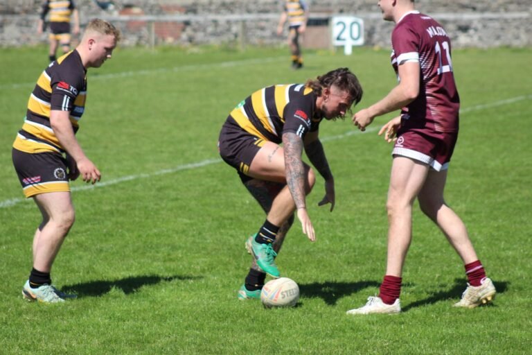 Two players competing for a loose ball against Millom